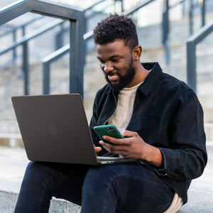 Spigen MacBook Air 13-inch Air Skin in Frost Black showing a person typing on a MacBook with the Frost Black case applied