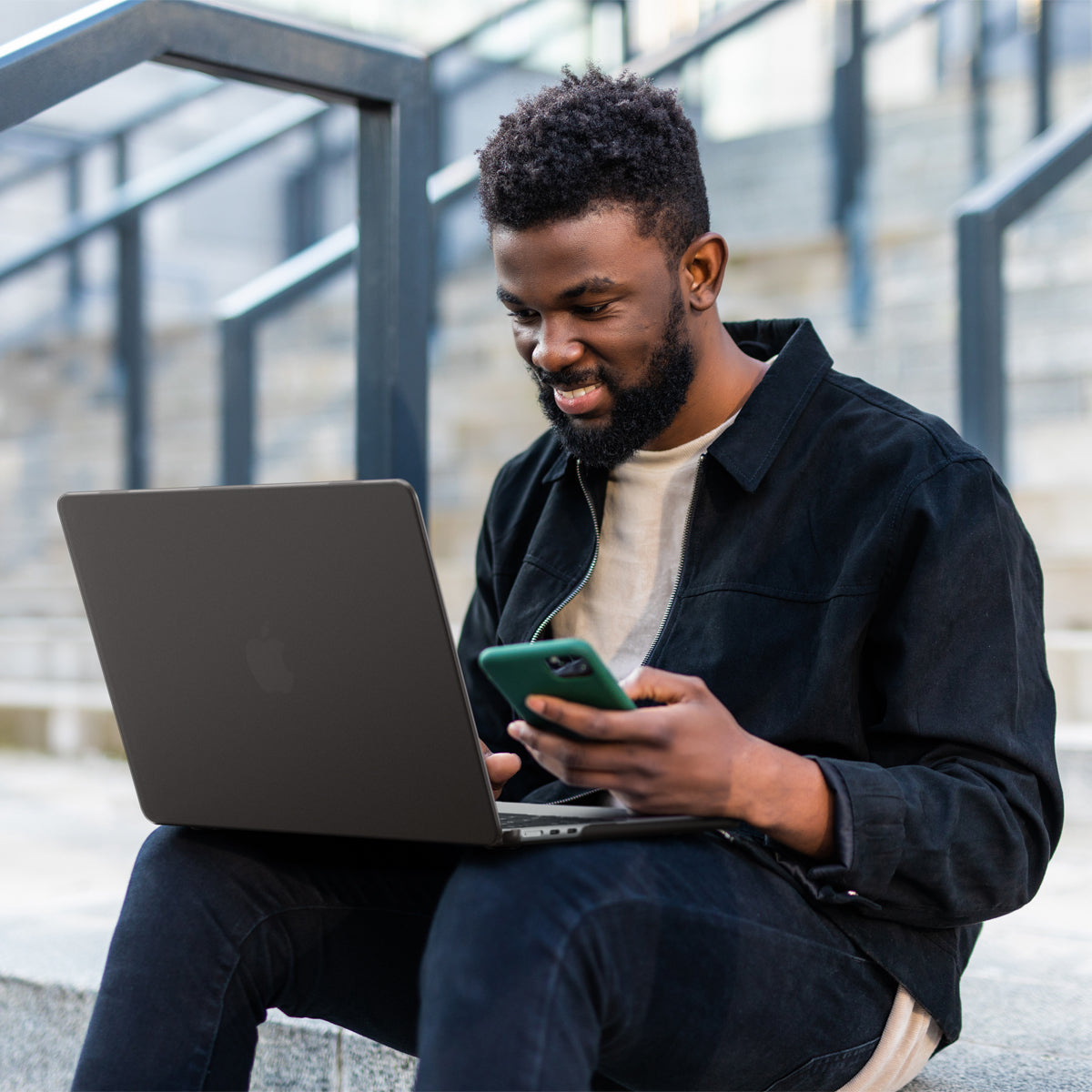 Spigen MacBook Air 13-inch Air Skin in Frost Black showing a person typing on a MacBook with the Frost Black case applied